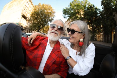 Photo of Senior couple enjoying cabriolet ride in city, wide angle lens