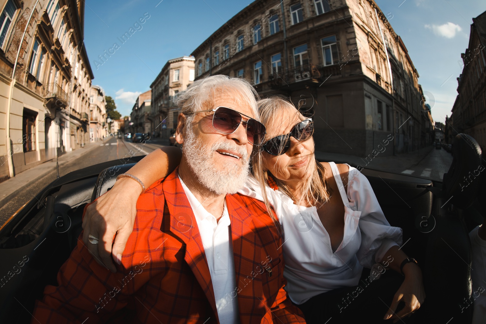 Photo of Senior couple enjoying cabriolet ride in city, wide angle lens
