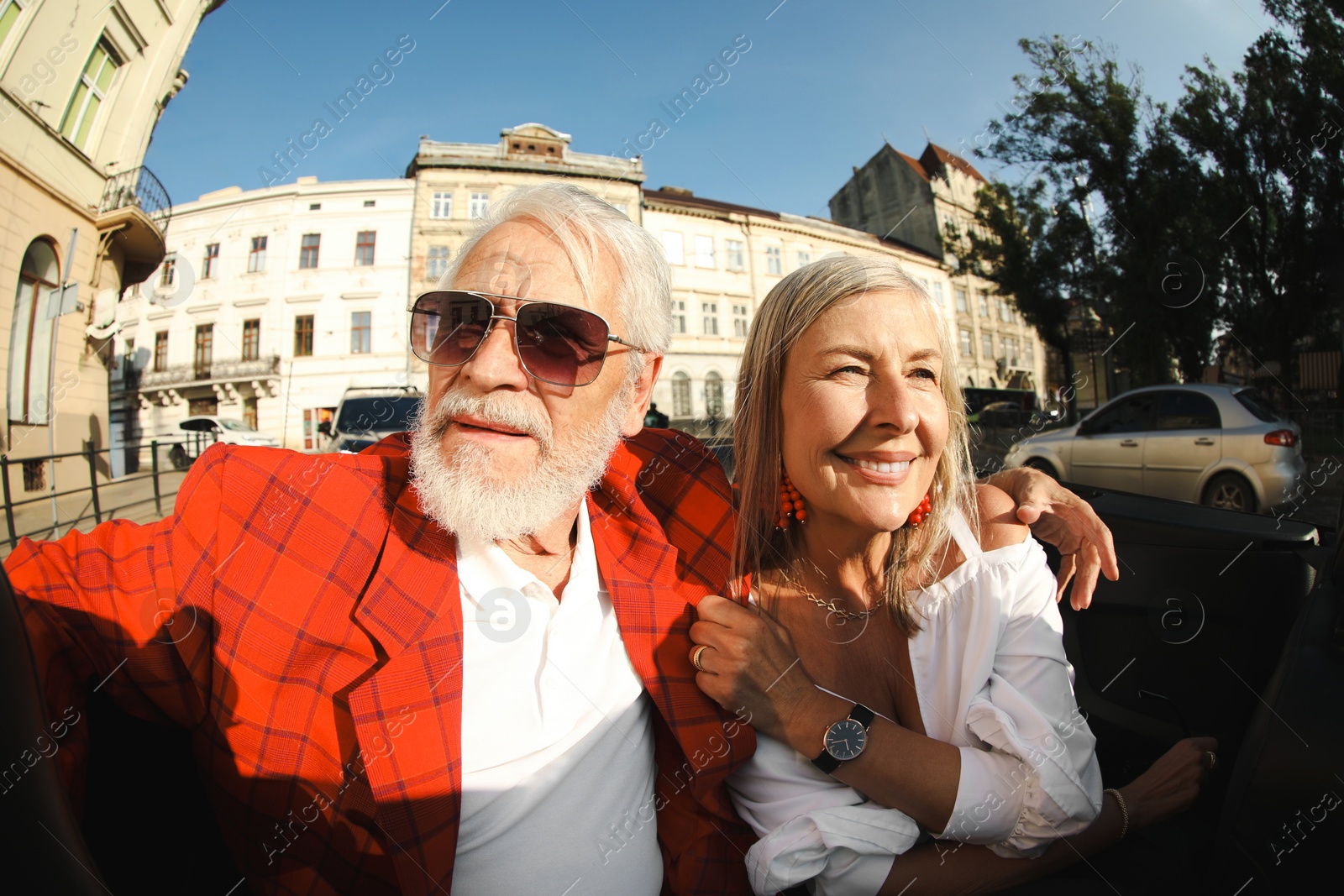 Photo of Senior couple enjoying cabriolet ride in city, wide angle lens