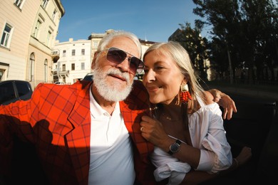Photo of Senior couple enjoying cabriolet ride in city, wide angle lens