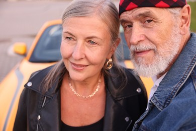 Photo of Stylish senior couple near modern cabriolet outdoors, closeup