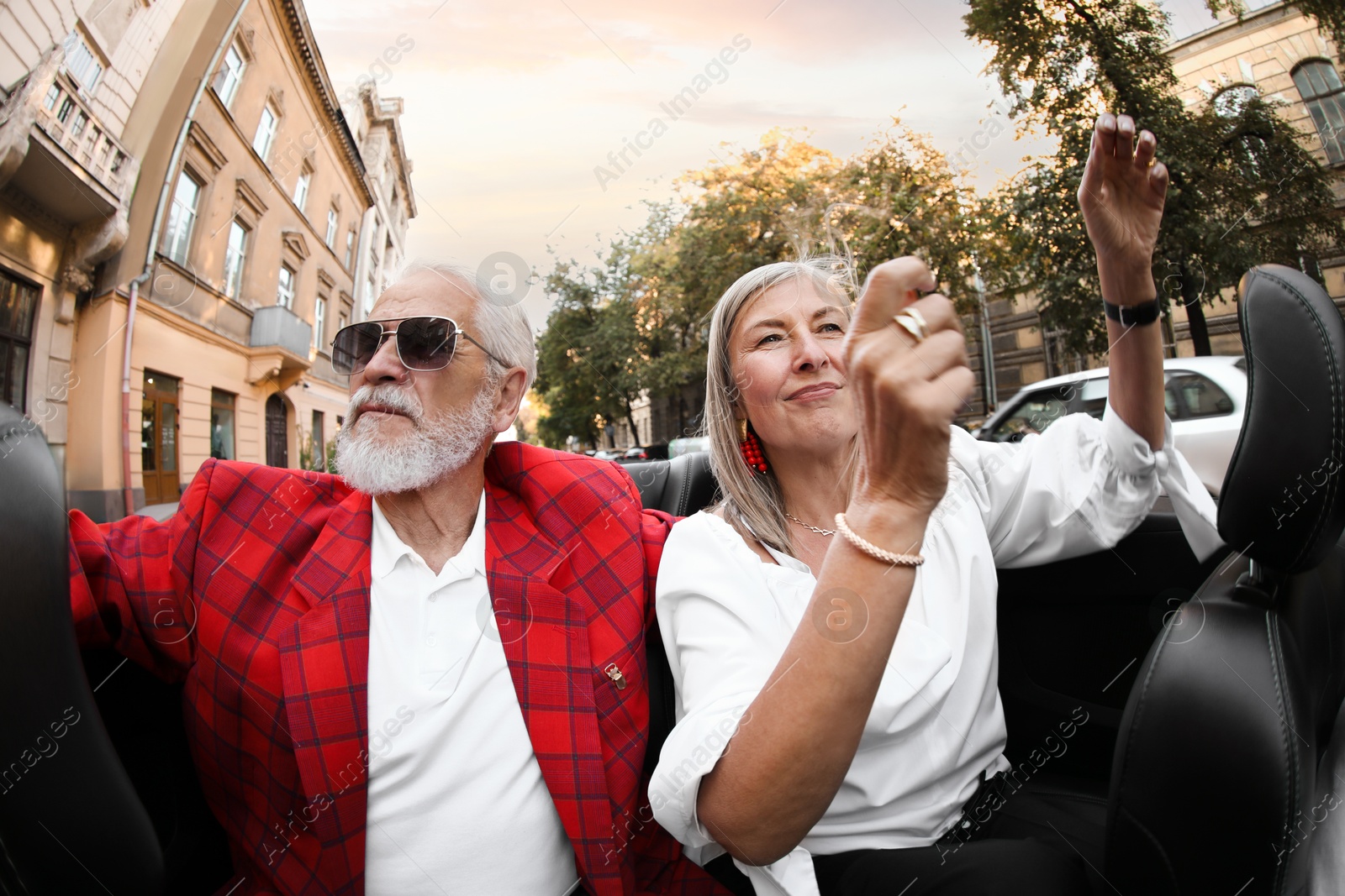 Photo of Senior couple enjoying cabriolet ride in city, wide angle lens