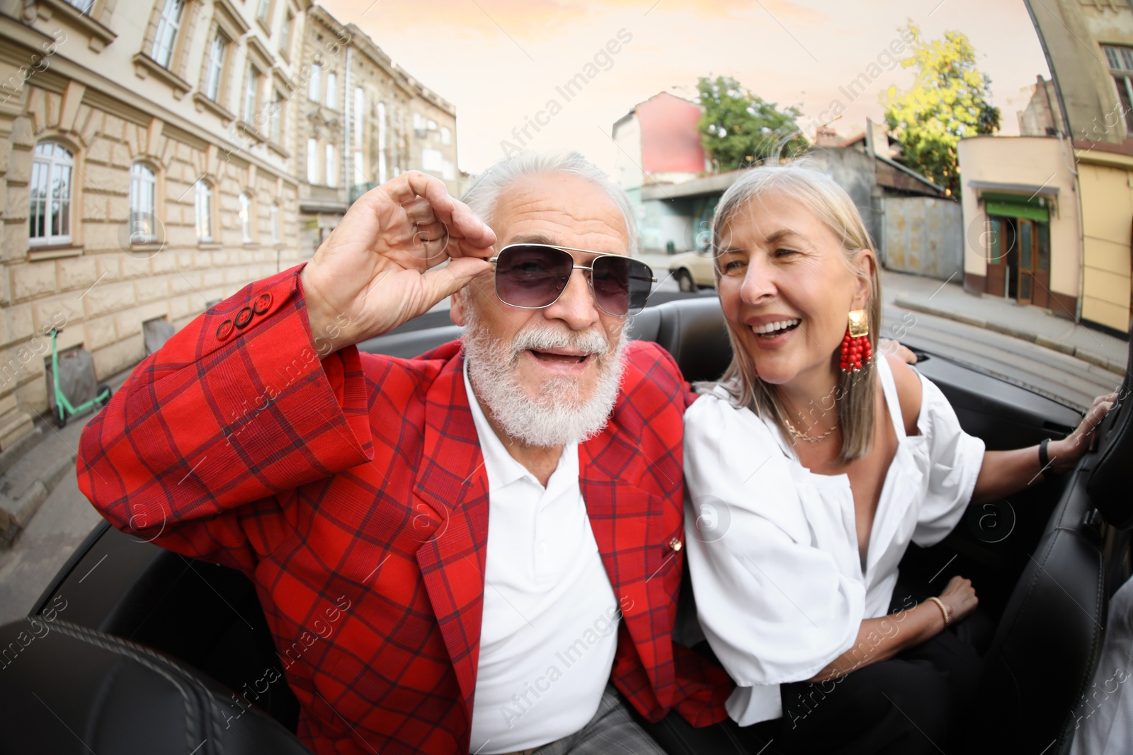 Photo of Senior couple enjoying cabriolet ride in city, wide angle lens