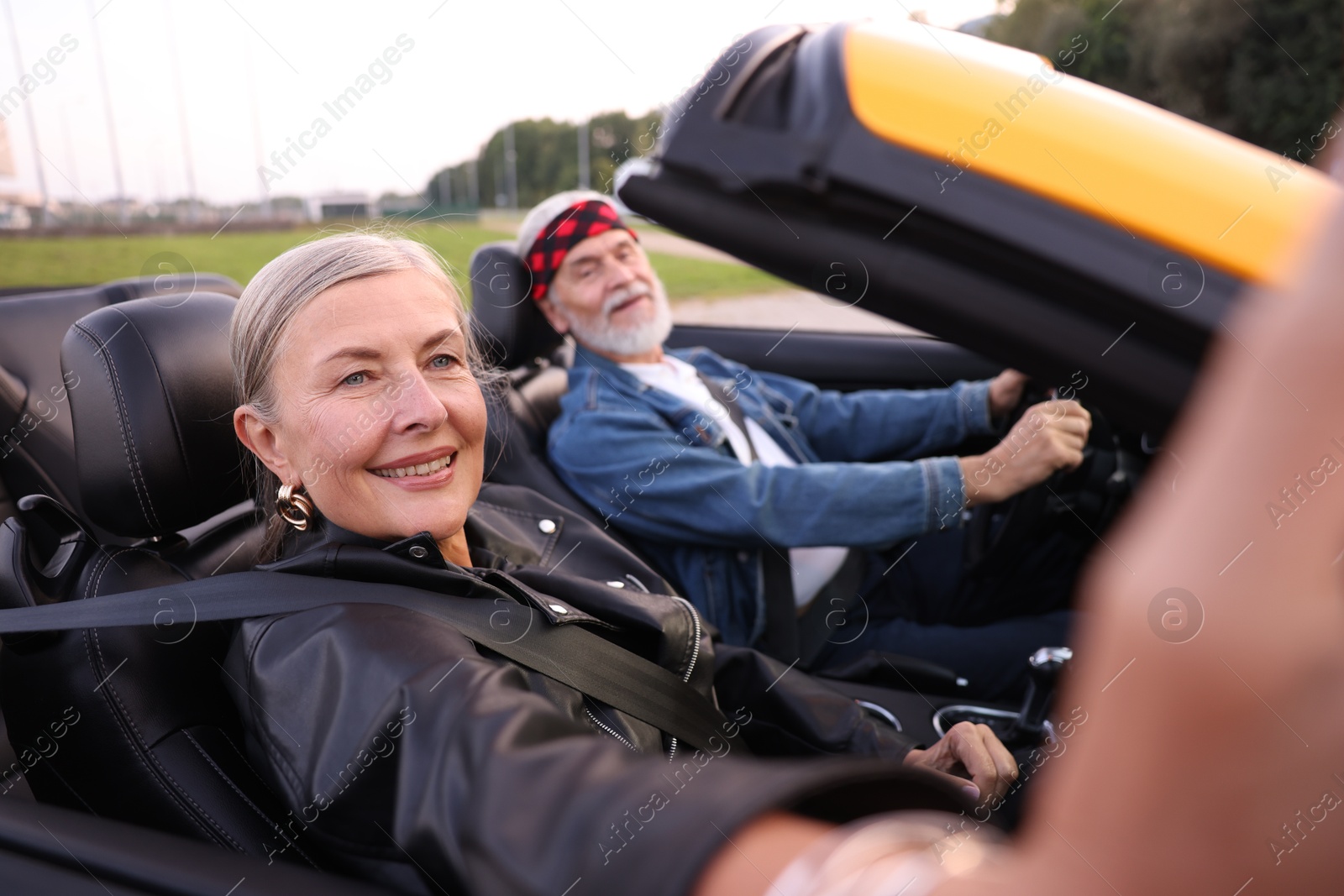 Photo of Senior woman taking selfie while man driving cabriolet outdoors, selective focus