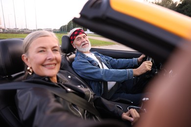 Photo of Senior woman taking selfie while man driving cabriolet outdoors, selective focus