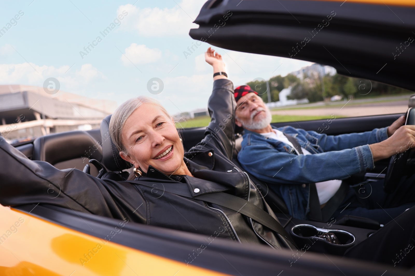 Photo of Stylish senior couple enjoying cabriolet ride outdoors, selective focus