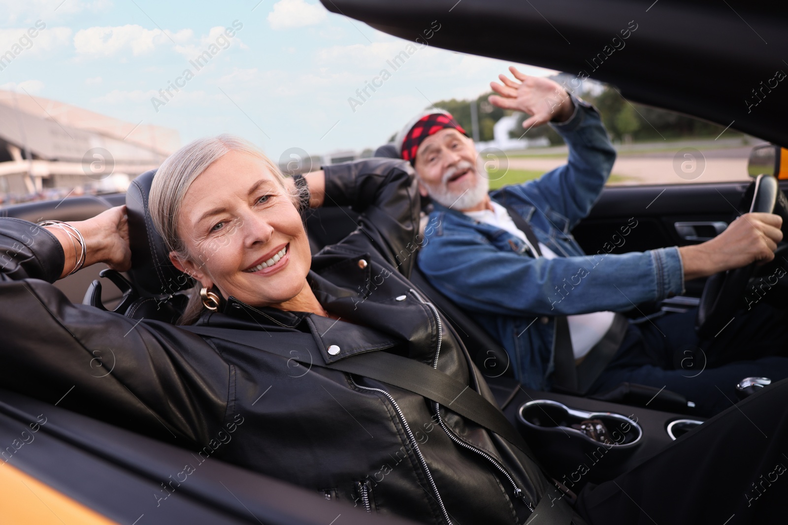 Photo of Stylish senior couple enjoying cabriolet ride outdoors, selective focus