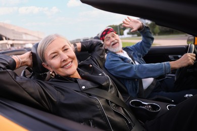 Photo of Stylish senior couple enjoying cabriolet ride outdoors, selective focus