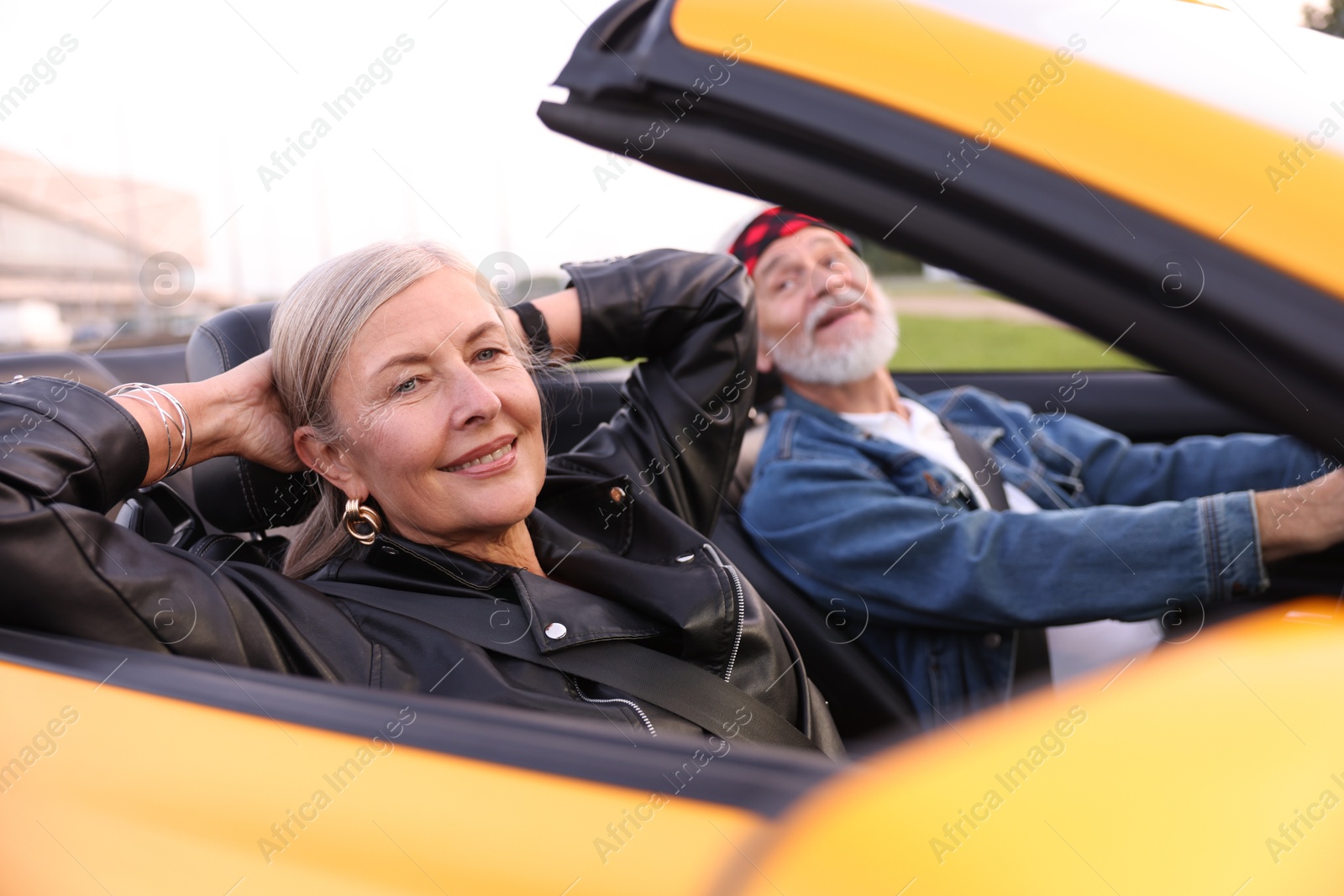Photo of Stylish senior couple enjoying cabriolet ride outdoors, selective focus