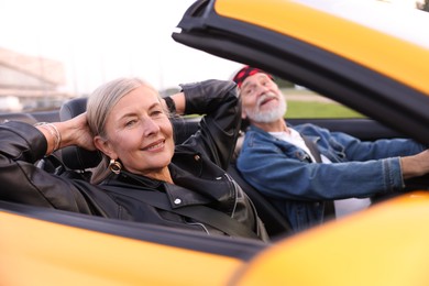 Photo of Stylish senior couple enjoying cabriolet ride outdoors, selective focus