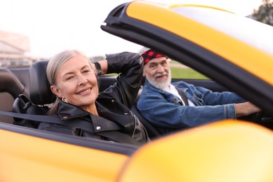 Photo of Stylish senior couple enjoying cabriolet ride outdoors, selective focus