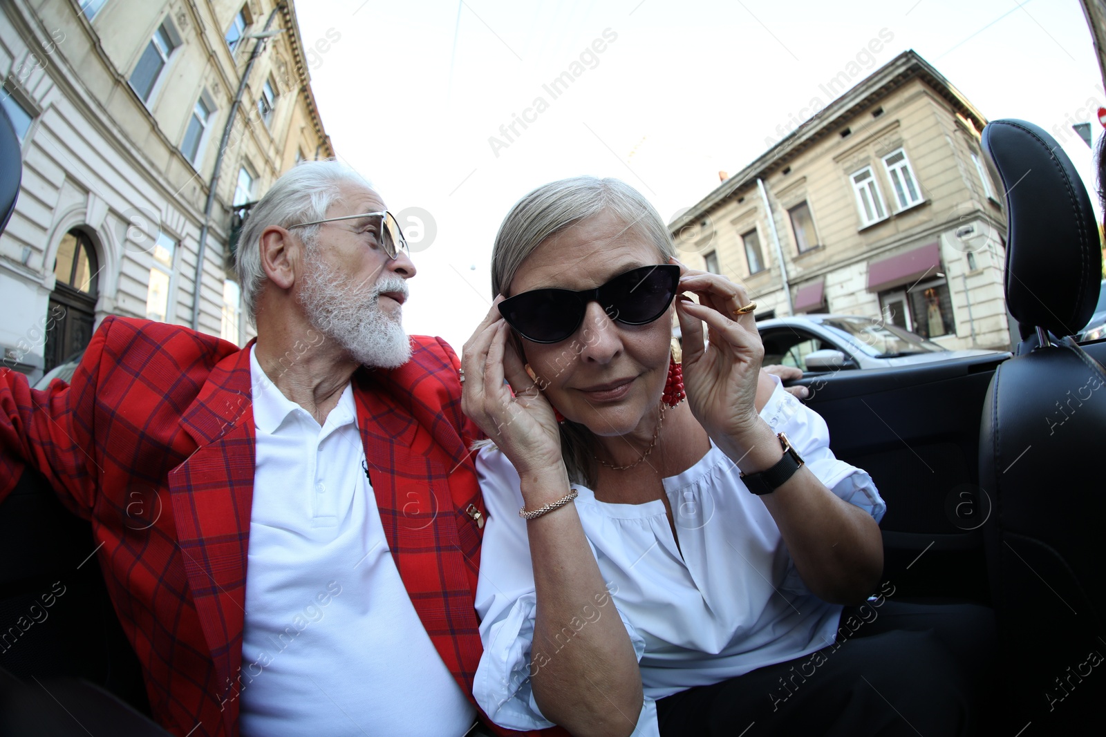 Photo of Senior couple enjoying cabriolet ride in city, wide angle lens