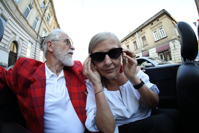 Photo of Senior couple enjoying cabriolet ride in city, wide angle lens