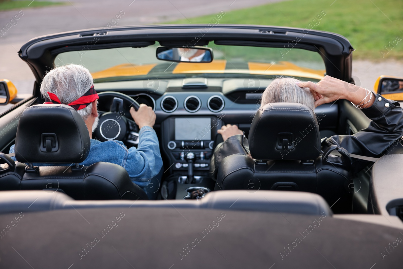 Photo of Stylish senior couple enjoying cabriolet ride outdoors, back view