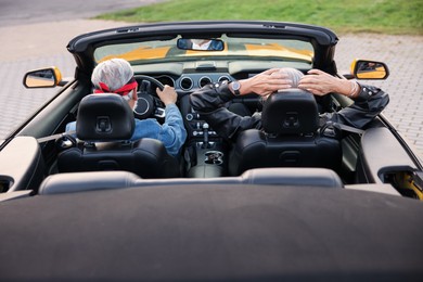 Photo of Stylish senior couple enjoying cabriolet ride outdoors, back view