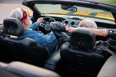 Photo of Stylish senior couple enjoying cabriolet ride outdoors