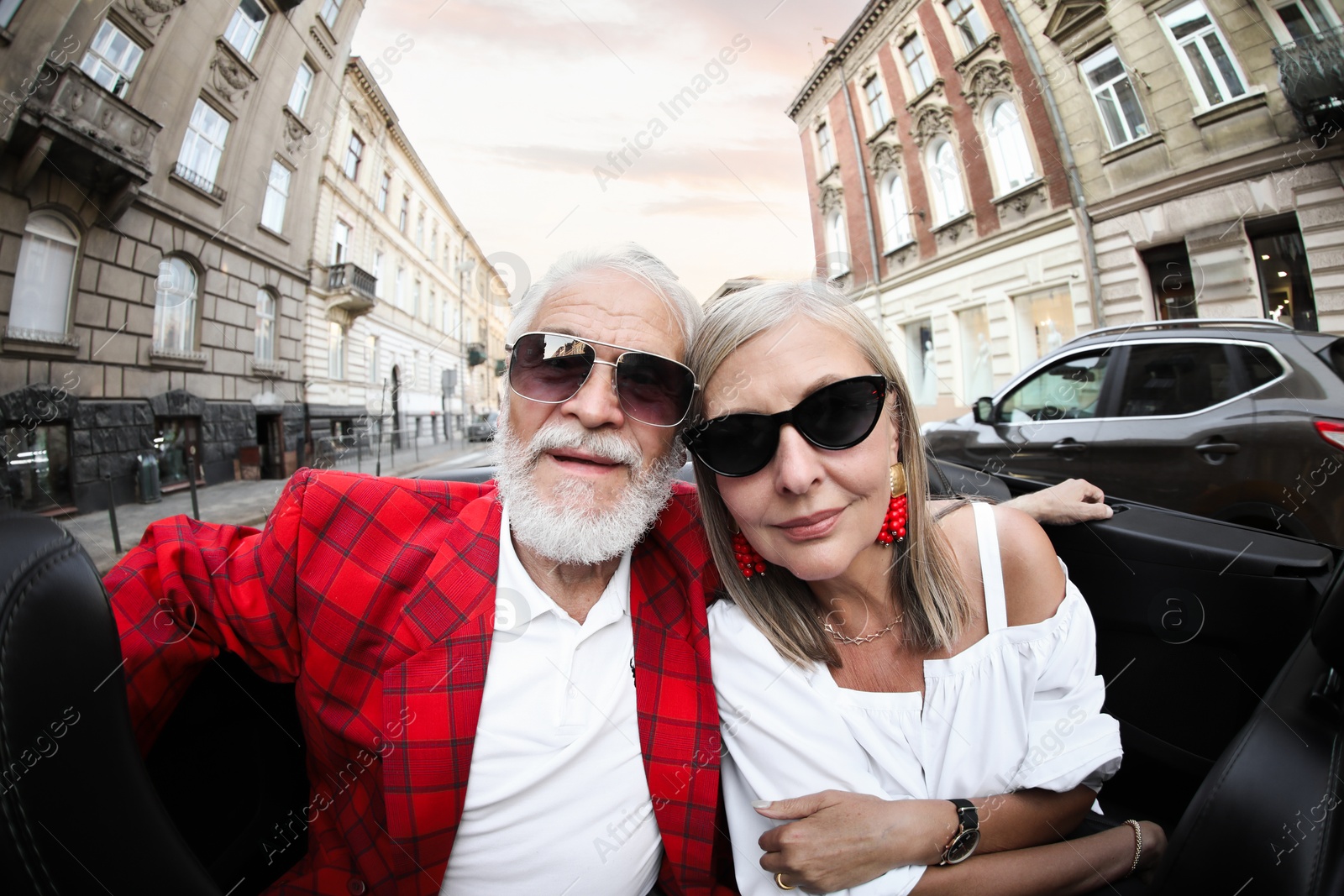 Photo of Senior couple enjoying cabriolet ride in city, wide angle lens