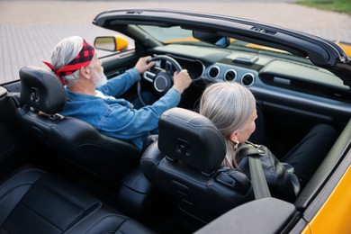 Photo of Stylish senior couple enjoying cabriolet ride outdoors