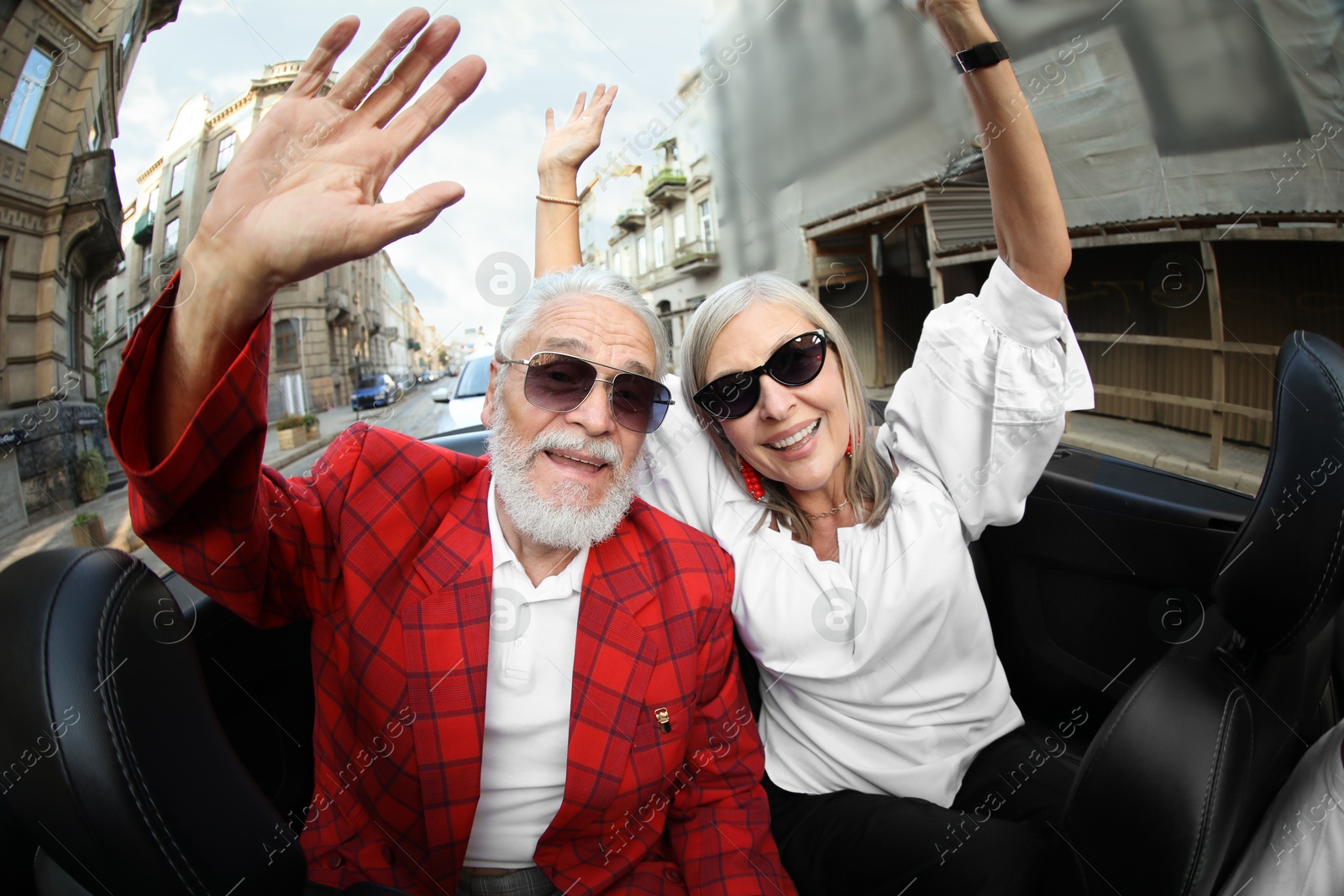 Photo of Senior couple enjoying cabriolet ride in city, wide angle lens