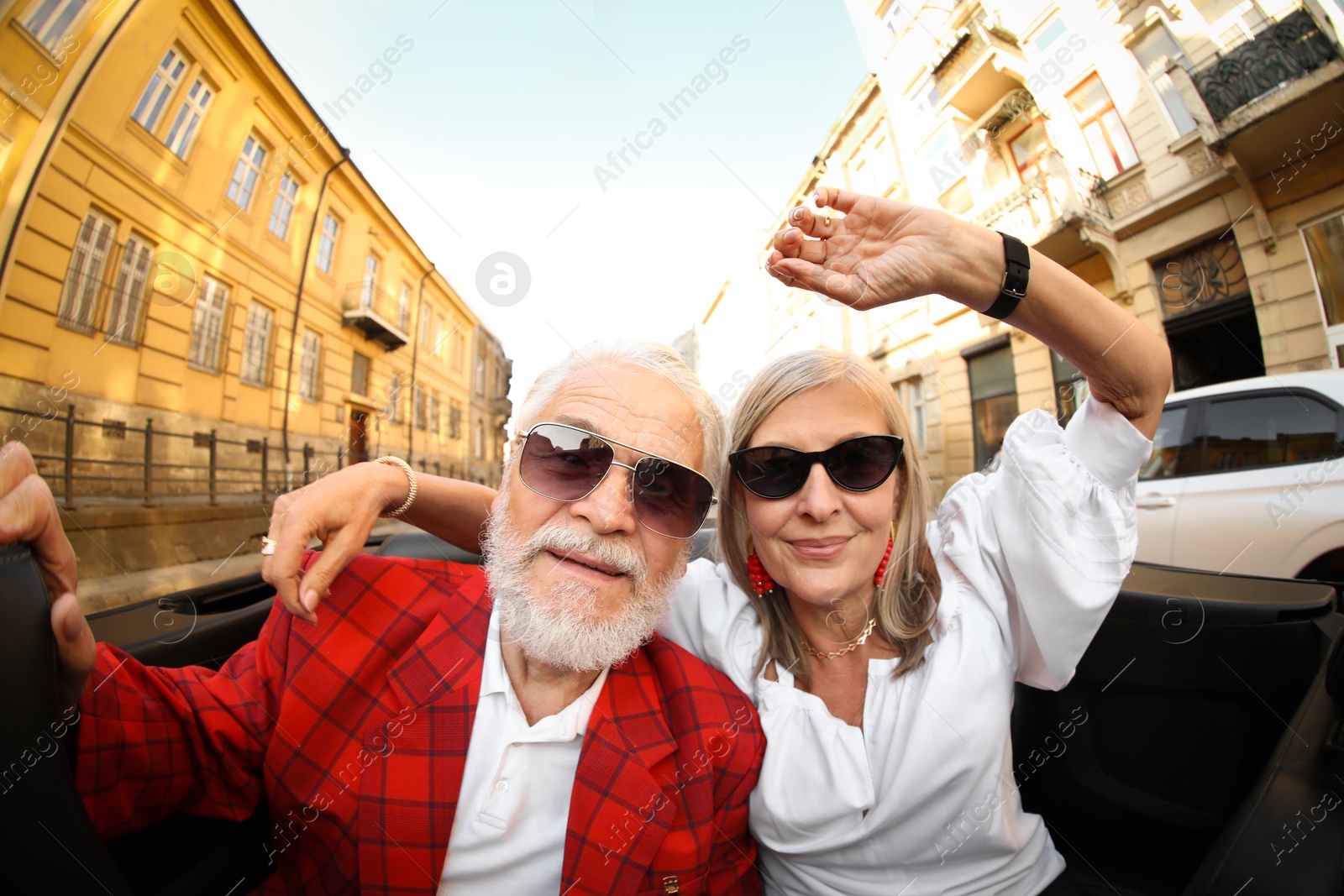 Photo of Senior couple enjoying cabriolet ride in city, wide angle lens