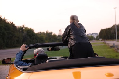 Photo of Senior couple enjoying cabriolet ride in city, back view