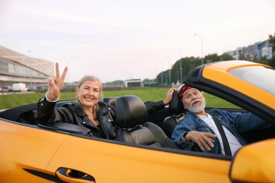 Photo of Stylish senior couple enjoying cabriolet ride in city