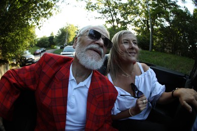 Photo of Senior couple enjoying cabriolet ride in city, wide angle lens
