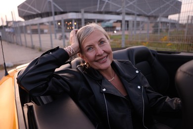 Photo of Stylish senior woman in modern cabriolet outdoors