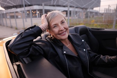 Photo of Stylish senior woman in modern cabriolet outdoors