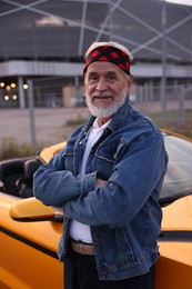 Photo of Stylish senior man near modern cabriolet outdoors