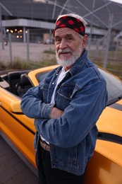 Photo of Stylish senior man near modern cabriolet outdoors