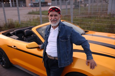 Photo of Stylish senior man near modern cabriolet outdoors