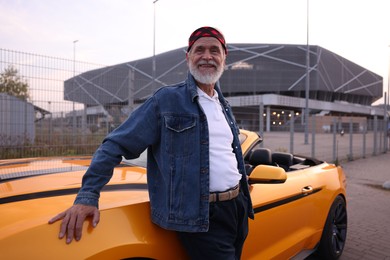 Photo of Stylish senior man near modern cabriolet outdoors