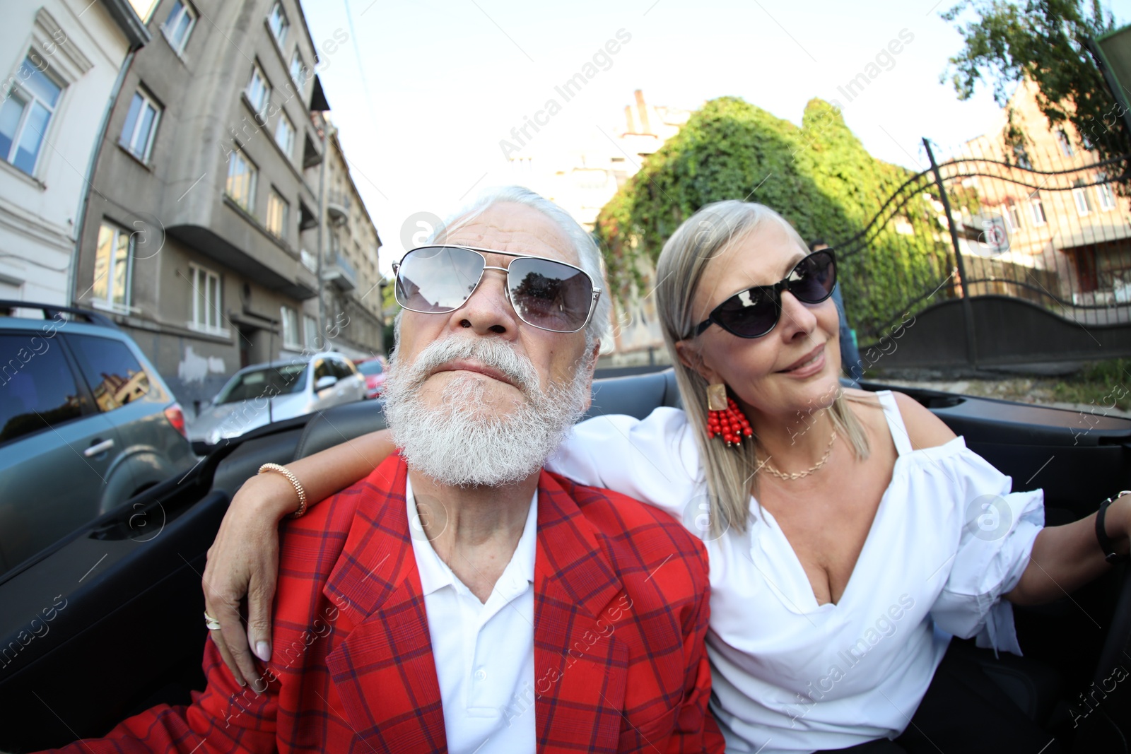 Photo of Senior couple enjoying cabriolet ride in city, wide angle lens