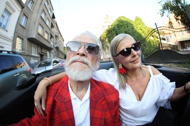 Photo of Senior couple enjoying cabriolet ride in city, wide angle lens