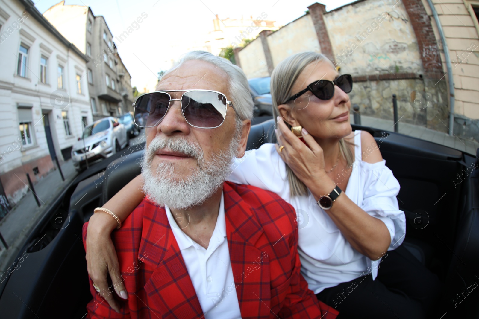 Photo of Senior couple enjoying cabriolet ride in city, wide angle lens