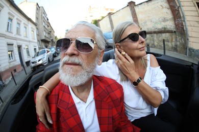 Photo of Senior couple enjoying cabriolet ride in city, wide angle lens