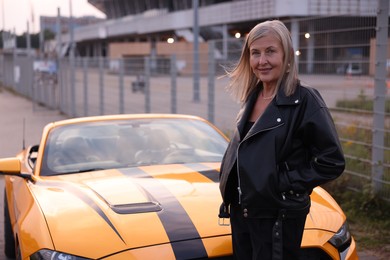 Photo of Stylish senior woman near modern cabriolet outdoors