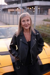 Photo of Stylish senior woman near modern cabriolet outdoors
