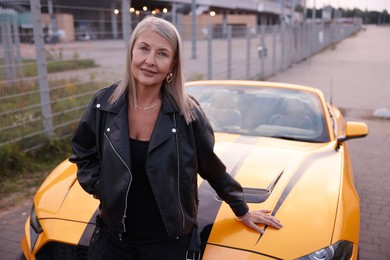 Photo of Stylish senior woman near modern cabriolet outdoors