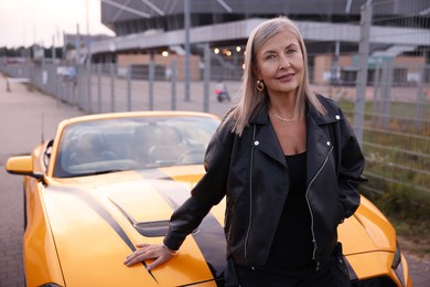 Photo of Stylish senior woman near modern cabriolet outdoors