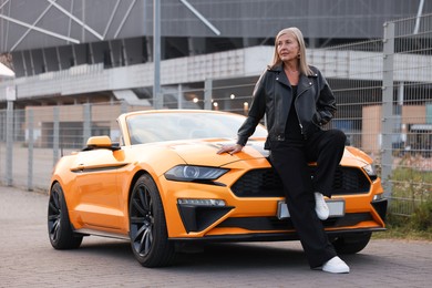 Photo of Stylish senior woman near modern cabriolet outdoors