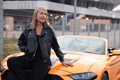 Photo of Stylish senior woman near modern cabriolet outdoors