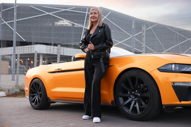 Photo of Stylish senior woman near modern cabriolet outdoors