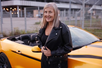 Photo of Stylish senior woman near modern cabriolet outdoors