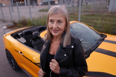 Photo of Stylish senior woman near modern cabriolet outdoors