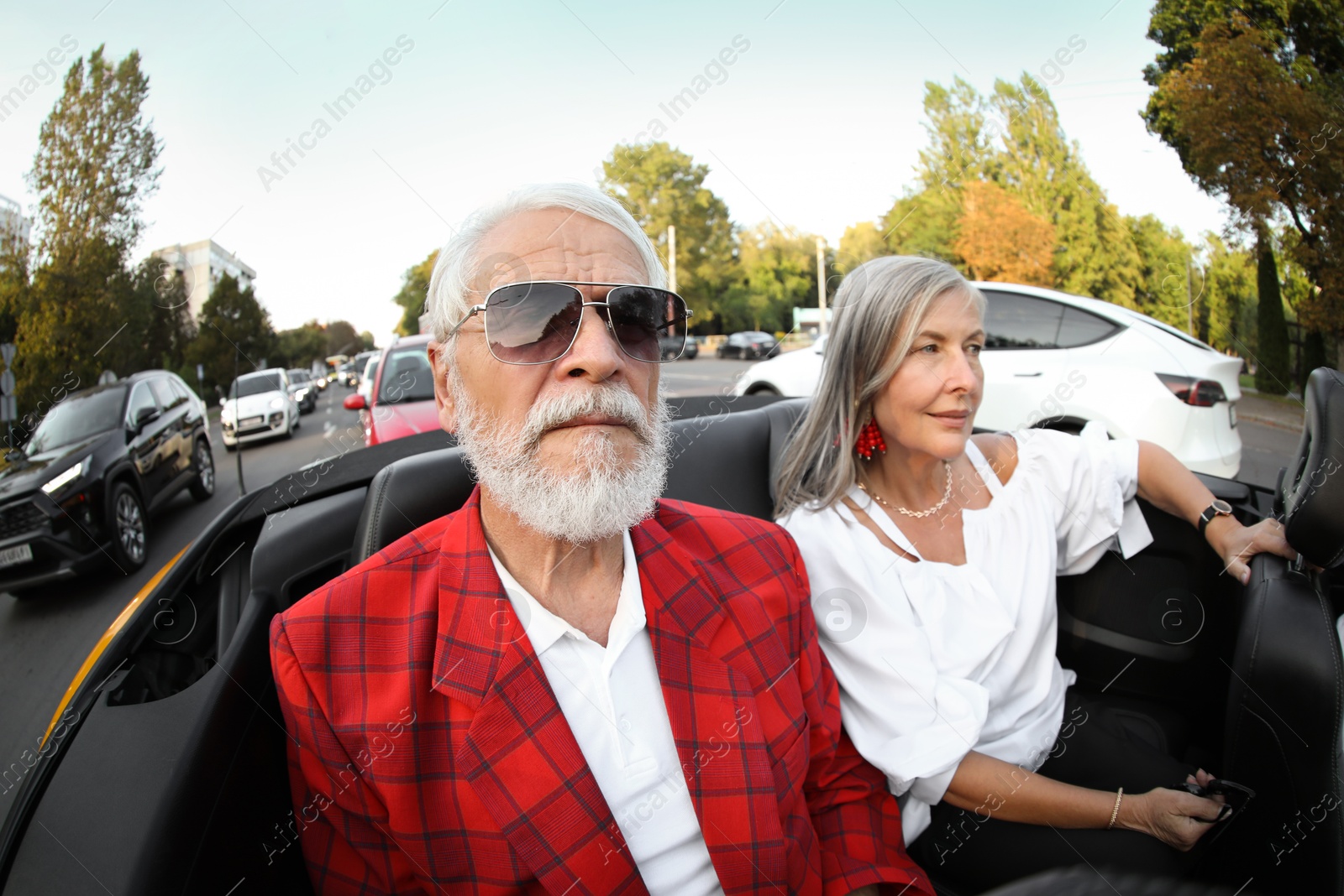 Photo of Senior couple enjoying cabriolet ride in city, wide angle lens