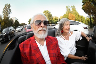 Photo of Senior couple enjoying cabriolet ride in city, wide angle lens