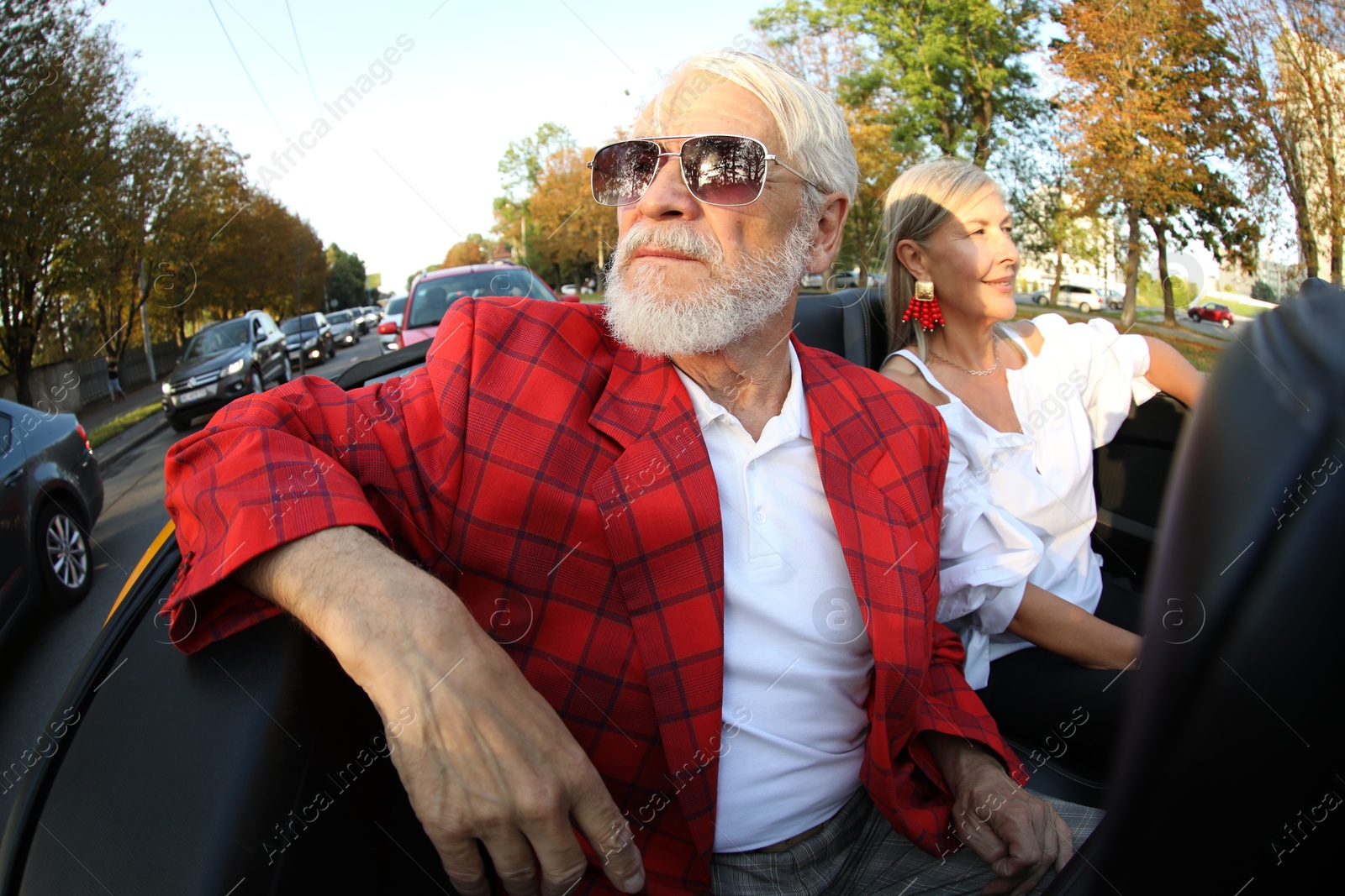 Photo of Senior couple enjoying cabriolet ride in city, wide angle lens