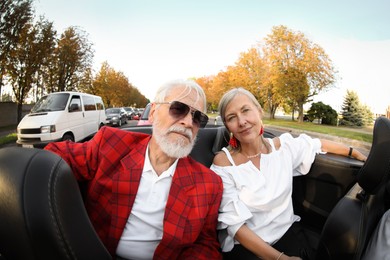 Photo of Senior couple enjoying cabriolet ride in city, wide angle lens